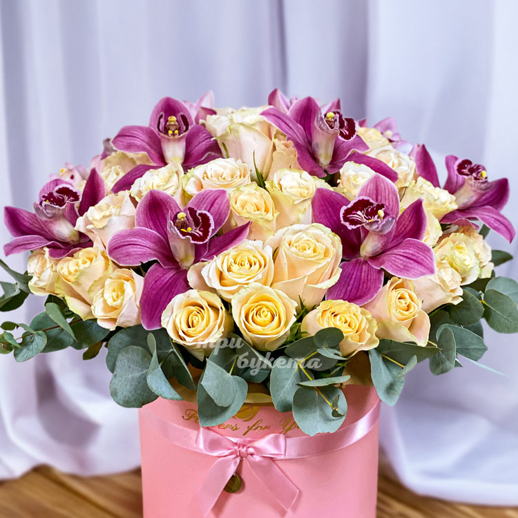 Коробка кремовых роз и бордовых орхидей (крупный план)